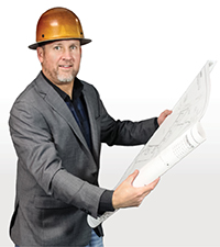 Chris Pingree wearing a hard hat and holding building plans