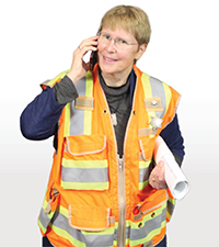 Kerrie Koski talking on a phone wearing a construction vest