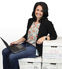 Mikki Huntsman with a laptop sitting on boxes