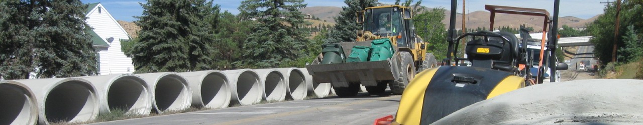 Cement storm drain pipes on road with tractors