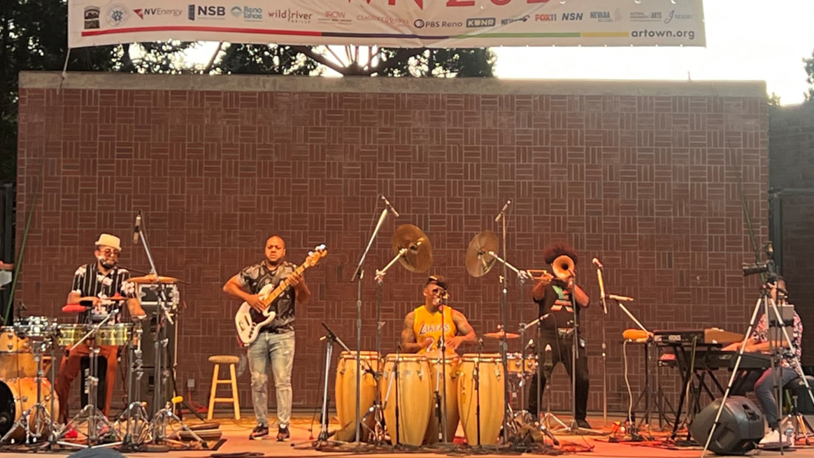 musicians including Pedrito Martinez performing on an outdoor stage 